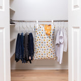 An organized closet with jeans, shirts, and a Bumkins Extra Large Wet Bag: Winnie + Friends with white walls and light wood floors.