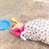 Beach toys spill out of a Bumkins Extra Large Wet Bag: Winnie + Friends laying on the sand.