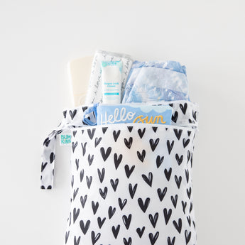 Bumkins Wet/Dry Bag: Hearts holds diapers, cream, and wipes on a white background.