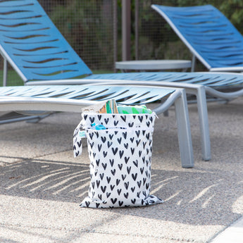 Bumkins Wet/Dry Bag: Hearts sits by blue lounge chairs, holding towels and pool essentials.