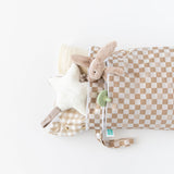 Bumkins Wet/Dry Bag: Sand Check holds a plush rabbit toy, star pillow, clothes, and blanket on a white background.