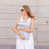Woman in sunglasses and white dress holds Bumkins Wet Bag + Wet/Dry Bag Set: Lunar Phase by a textured beige wall.
