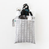 Bumkins Wet/Dry Bag: Lunar Phase holds gym essentials like a bottle, phone, towel, clothes and toiletries on a white background.