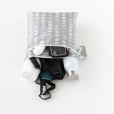 Bumkins Wet/Dry Bag: Lunar Phase lays on a white background, filled with gym essentials like clothes, a towel, a phone, and a water bottle.