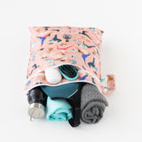 The Bumkins Wet Bag + Wet/Dry Bag Set: Yoga Pals holds bottles, brush, towel, clothes & toiletries on a white surface.