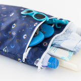 Close-up of Bumkins Wet/Dry Bag: Evil Eye, holding sunglasses, shoes, sunscreen, diapers, and toys on a white background.