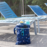 The Bumkins Wet Bag + Wet/Dry Bag Set in Evil Eye sits poolside, packed and ready for a sunny day outdoors.