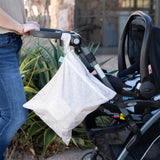 A person pushes a stroller outdoors with a Bumkins Wet Bag + Wet/Dry Bag Set: Wander, hanging from the handle.