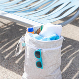 The Bumkins Wet Bag + Wet/Dry Bag Set: Wander sits by a modern lounge chair, ready for your outdoor adventures.