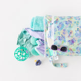Bumkins Wet/Dry Bag: Aloha Stitch holds a teal towel, swimsuit, pacifier, toy ball and sunglasses on a white background.