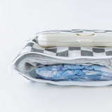 Bumkins Wet/Dry Clutch: Charcoal Check lays open on a white background with diapers, clothes, and wipes inside.