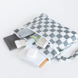 Bumkins Wet Bag + Wet/Dry Clutch + Clear Travel Bag 3 Pack in Charcoal Check shown with travel essentials on a white surface.