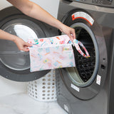 A person holds a Bumkins Wet/Dry Clutch: Boots in front of a front-loading washing machine.