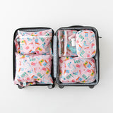 An open suitcase on a white background with Bumkins Wet/Dry Clutch: Boots inside next to other matching bags.