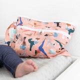 Close-up of a Bumkins Wet/Dry Clutch: Yoga Pals beside a baby's leg on a gray changing pad.