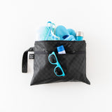 Bumkins Wet/Dry Clutch: Rich Black with blue sunglasses, a towel, shoes, a bottle, and sunscreen against a white background.