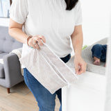 A person holds a Bumkins Wet/Dry Clutch: Wander, standing by a changing table with their baby.