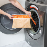 A person holds a Bumkins Wet/Dry Clutch: Grounded in front of a a front-loading washer.