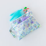 Bumkins Wet/Dry Clutch: Aloha Stitch holds turquoise bags, a purple bowl with matching spoon, and an applesauce pouch on a white background.