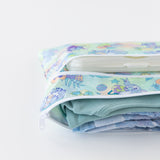 A bag from Bumkins Wet Bag + Wet/Dry Clutch Set: Disney Aloha Stitch lays partially open on a white background, revealing clothes & diapers.