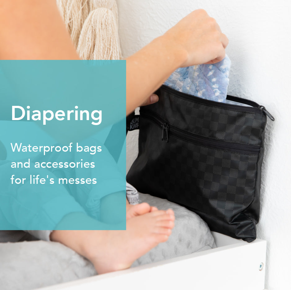 A woman pulling a diaper out of Bumkins Wet/Dry Clutch in Rich Black print to change her baby.