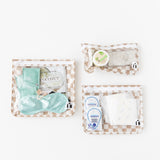 Roamio by Bumkins Clear Travel Bag 3 Pack: Sand Check is neatly arranged on a white background with toiletries inside.