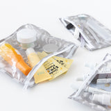 Bumkins Clear Travel Bag 3 Pack: Lunar Phase filled with skincare sachets and toiletries on a white background.