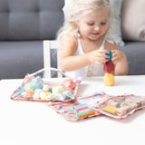 A young child stacks blocks at a table, with Bumkins Yoga Pals Wet Bag + Clutch + Travel Bag 3 Pack Set nearby.