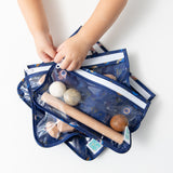 A child opens a Bumkins Wet Bag + Clear Travel Bag 3 Pack Set: Evil Eye—ideal for organizing toys and more on the go.