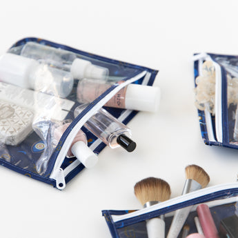 Bumkins Clear Travel Bag 3 Pack: Evil Eye filled with makeup and toiletries are displayed on a white background.