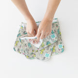 Hands use a cloth to clean the interior of Bumkins Clear Travel Bag 3-Pack: Cacti on a white background.