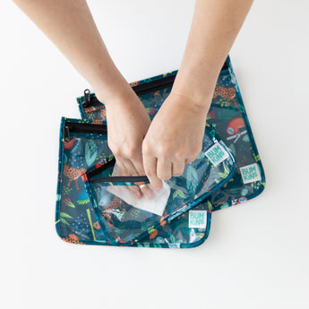 A person uses a cloth to clean the interior of Bumkins Clear Travel Bag 3-Pack: Jungle on a white background.