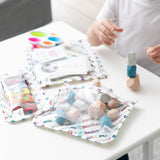 A child stacks blocks at a table with Bumkins Chaos Coordinator Deluxe 5-Piece Set: Disney Mickey & Friends Varsity bags.