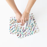 Hands wipe the interior of Bumkins Clear Travel Bag 3 Pack: Mickey & Friends Varsity with a cloth on a white background.