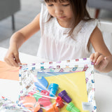 A girl in a white top zips Bumkins Clear Travel Bag 3 Pack: Mickey & Friends Varsity filled with art supplies.