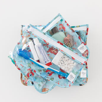 Bumkins Clear Travel Bag 3 Pack: Disney Princess Ariel holds toiletries like a toothbrush, toothpaste, shampoo, and mints on a white background.
