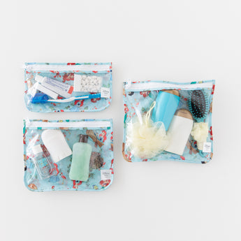 Bumkins Clear Travel Bag 3 Pack: Disney Princess Ariel filled with toiletries, mints, deodorant, and a hairbrush on a white background.