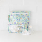 The Bumkins Wet Bag + Clear Travel Bag 3 Pack Set in Disney Aloha Stitch holds pump parts and tubing on a white surface.