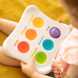 Child engaged with the Dimpl Duo by Fat Brain Toy Co, exploring textured, colorful shape buttons: circle, square, triangle, oval & more.
