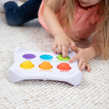 A child explores senses with the colorful Dimpl Duo shape sorter by Fat Brain Toy Co on a light carpet.