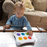 A toddler explores with the Dimpl Duo by Fat Brain Toy Co on a metal table in the living room.