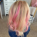 Blonde hair with Piggy Paint Pink highlights on someone in a navy polka dot shirt. Drawers and a basket in the background.