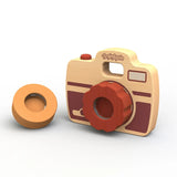 The Shutterbug Camera by Begin Again is a sustainably harvested rubberwood toy with red accents and an orange lens. Detachable viewfinder included.