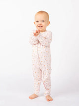 A baby stands clapping in Emerson and Friends’ Sleeper, Sweet Blooms bamboo pajamas, smiling against a plain white background.