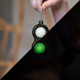 A hand with a Fat Brain Toy Co Simpl Dimpl Glow-in-the-Dark adds magic and tactile fun to your essentials.