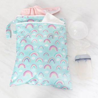 Bumkins Wet/Dry Bag: Rainbows holds a pink diaper and white cloth on a marble surface next to a breast pump.