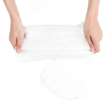Hands hold Bumkins Diaper Liners on a white background, demonstrating their 100% viscose design.