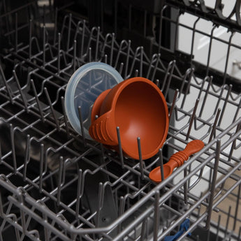 Bumkins Silicone First Feeding Set: Clay sits in the top rack of an open dishwasher.