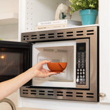 A person places a Bumkins Silicone First Feeding Set: Clay into an open microwave.