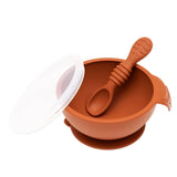 Bumkins Silicone First Feeding Set: Clay includes a bowl with suction bottom, a matching spoon, and a transparent lid.